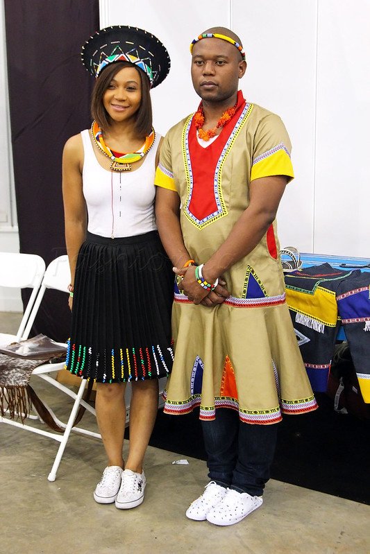Zulu hat, necklace, white tank top, beaded skirt, beaded necklace & converse: Men’s colourful dress over jeans & trainers